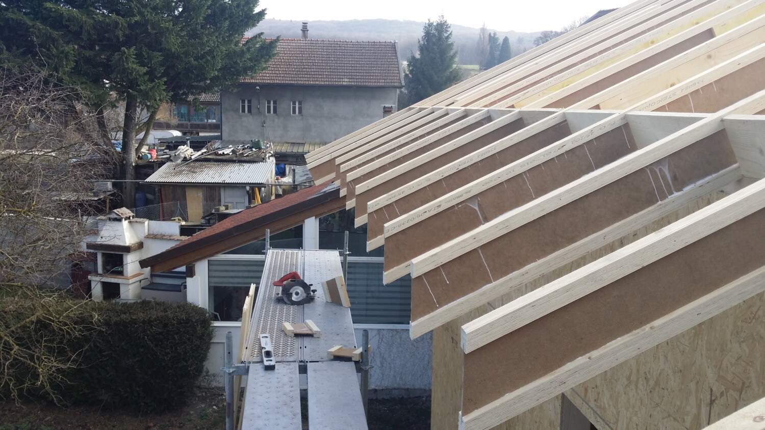 Charpentier installant une structure de toit en bois sur un chantier de construction.