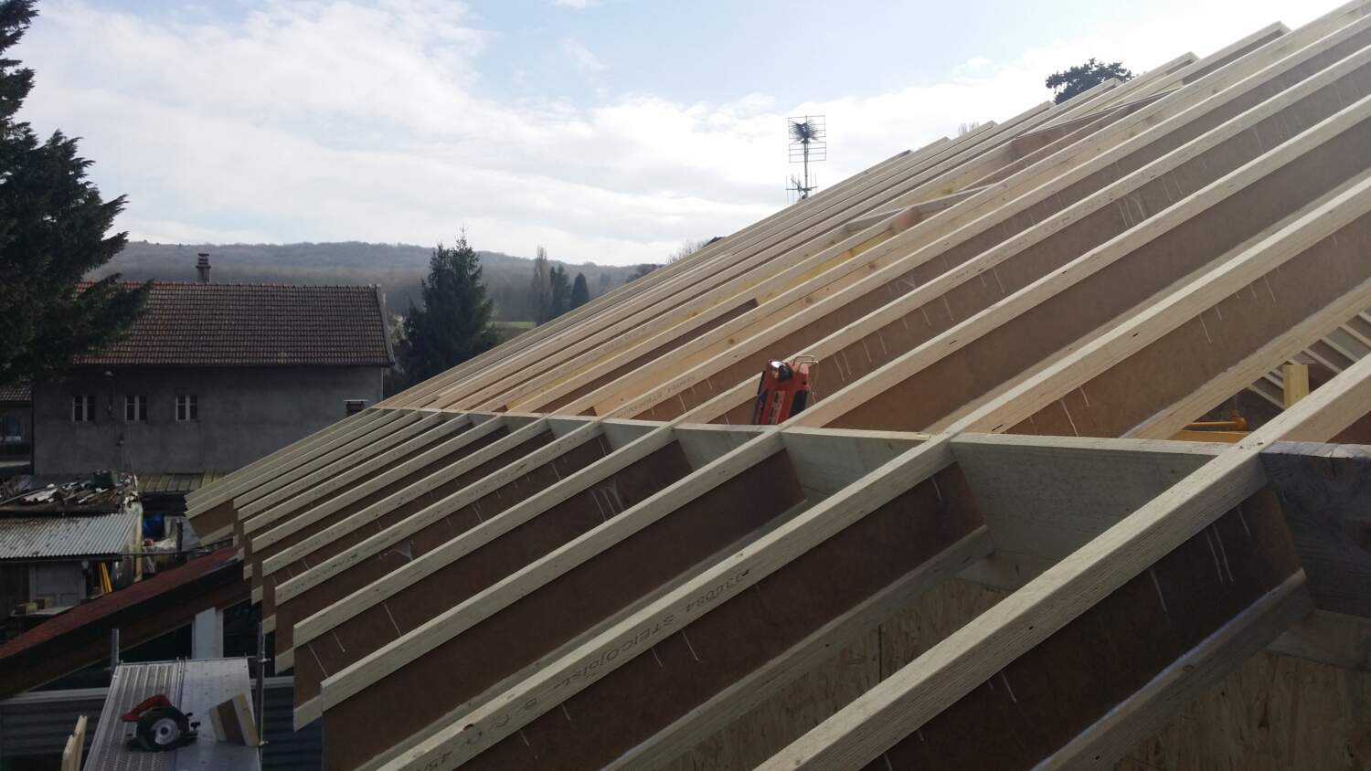 Charpentier installant des solives de toit sur un chantier de construction.