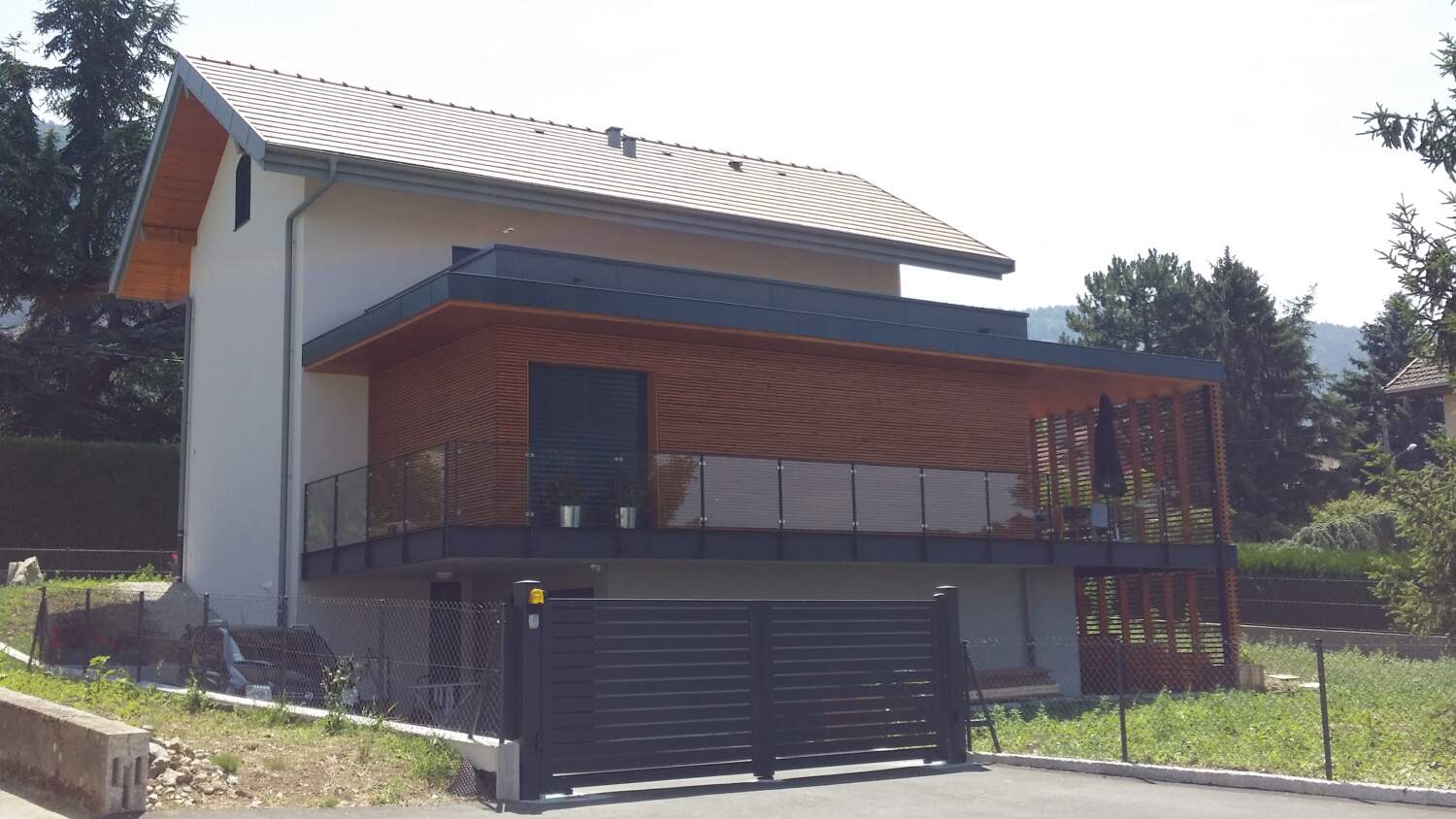 Maison moderne avec bardage en bois et balcon en verre en construction