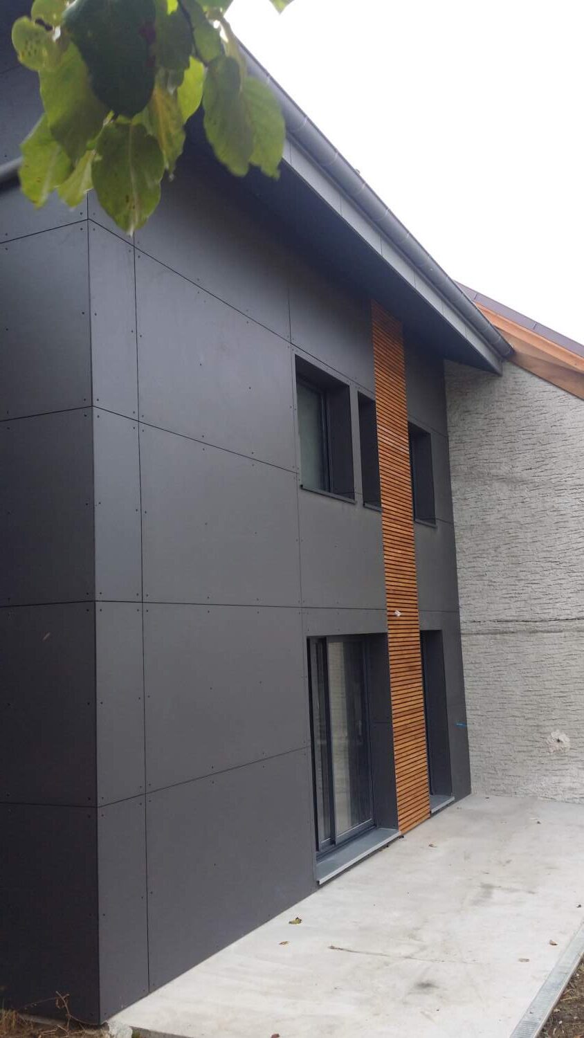 Extérieur de maison moderne avec bardage en bois et grandes fenêtres.