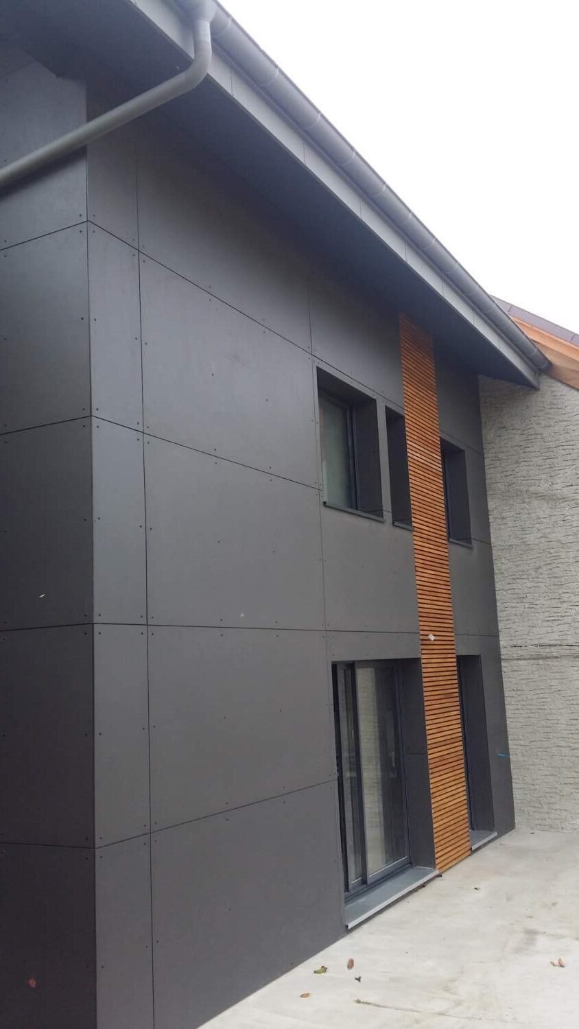 Charpentier installant un bardage en bois sur l'extérieur d'une maison.