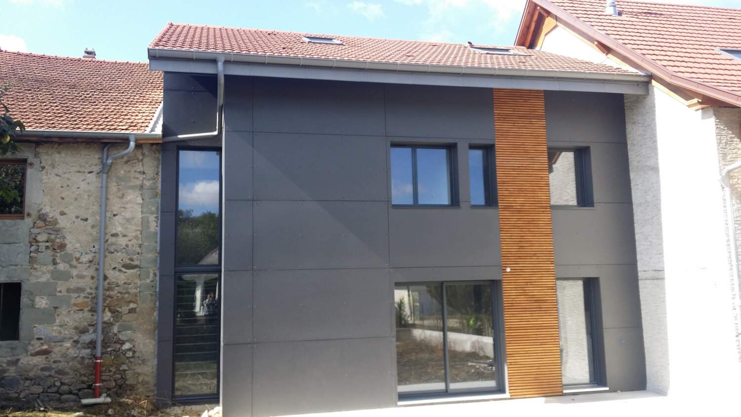 Rénovation de maison moderne avec bardage en bois et grandes fenêtres.