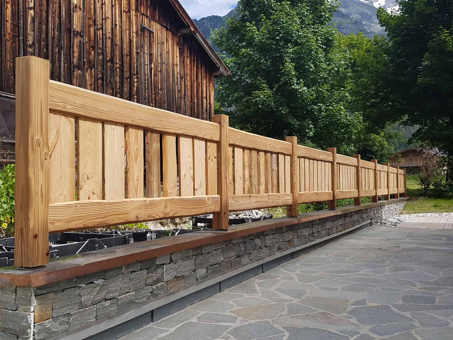Installation de rambarde en bois sur un mur en pierre.