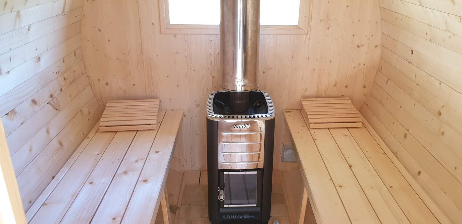 Intérieur de sauna en bois avec poêle Harvia et banquettes.