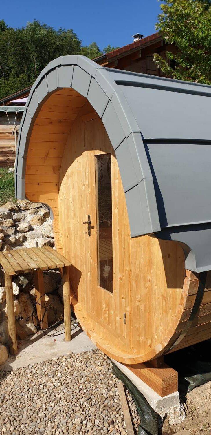 Charpentier installant une porte en bois à l'extérieur d'un sauna.
