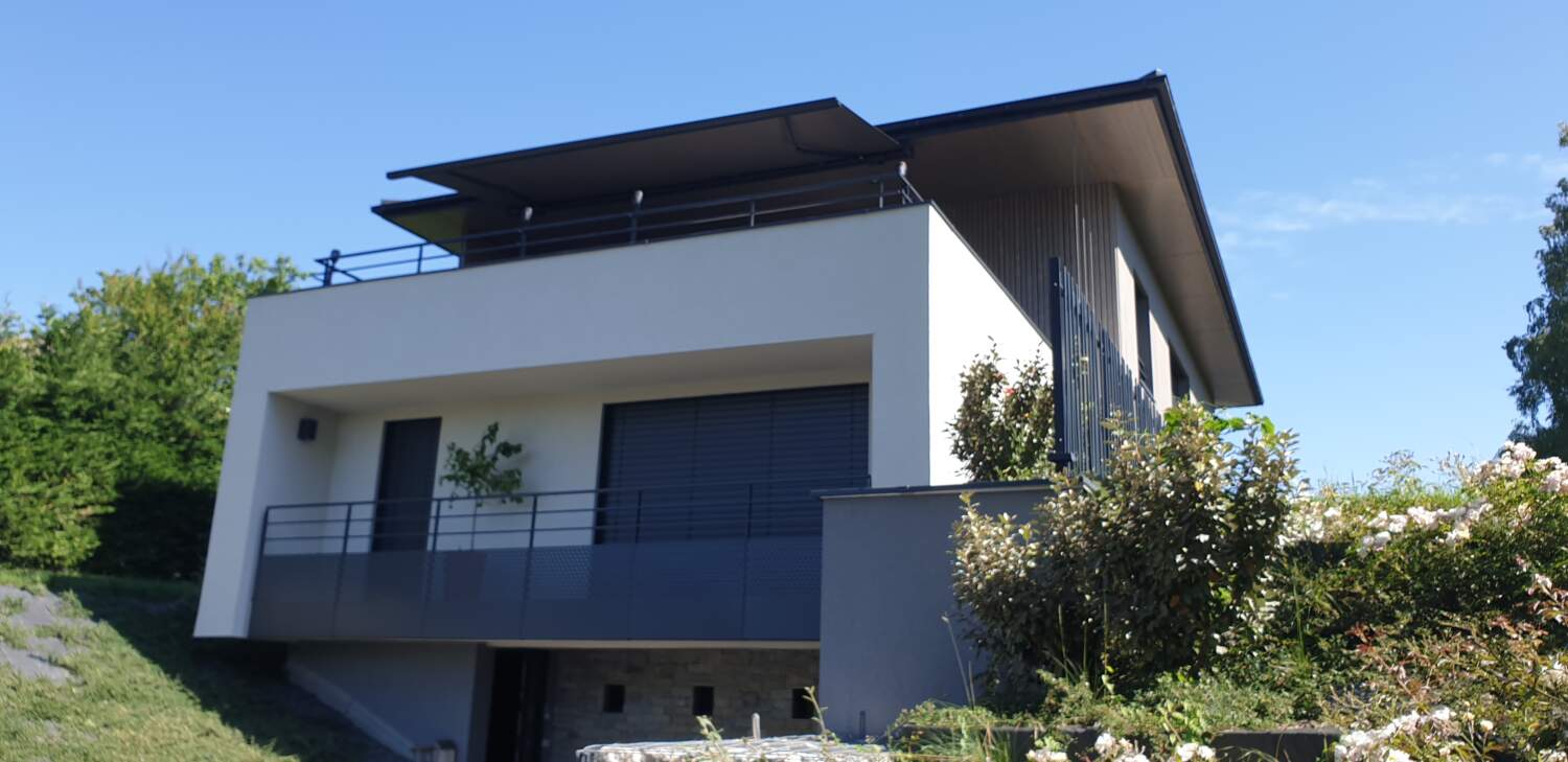 Maison moderne avec rampes en métal et grandes fenêtres.
