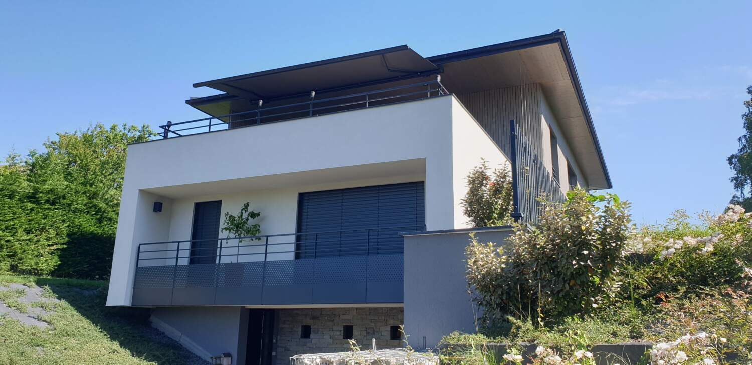 Maison moderne avec rampes en métal et grandes fenêtres.