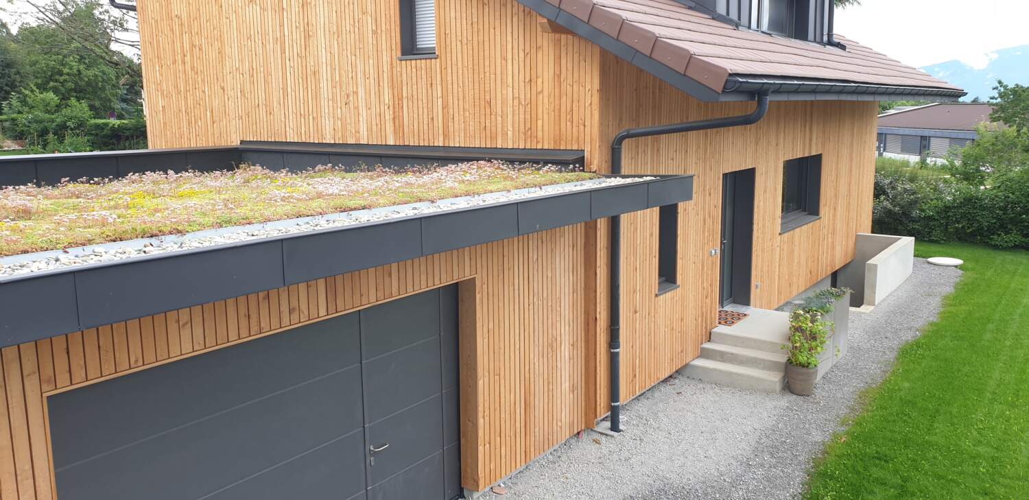 Maison en bois moderne avec toit vert sur un chantier de construction.
