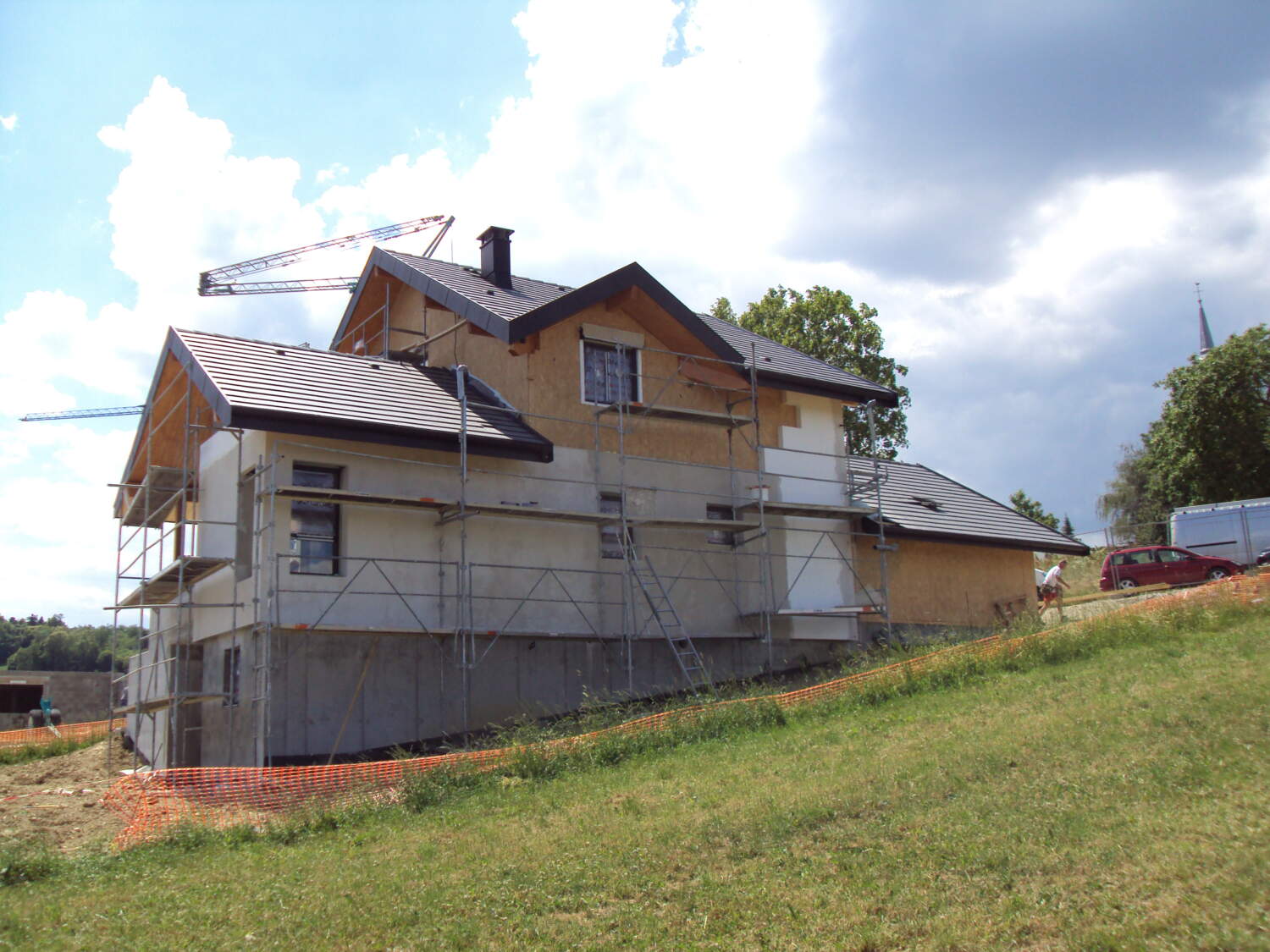 Construction de maison avec ossature en bois et travaux de couverture en cours.