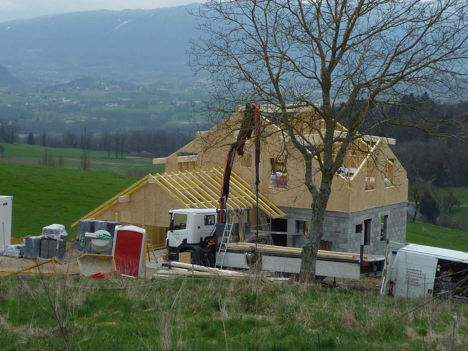 Charpentier installant des fermes de toit sur une maison en construction.