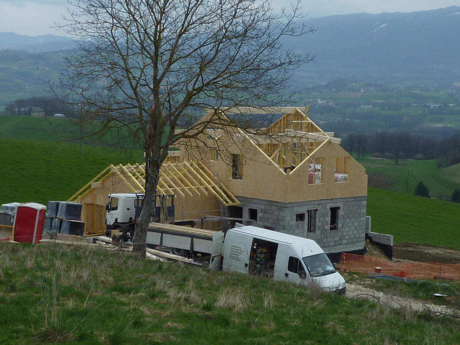 Charpentier installant des fermes de toit sur une maison en construction.