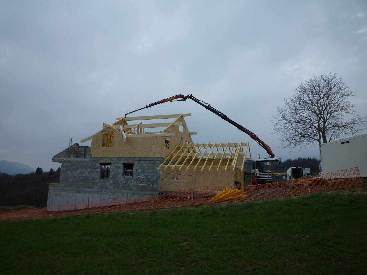 Charpentier installant des fermes de toit sur une maison en construction.