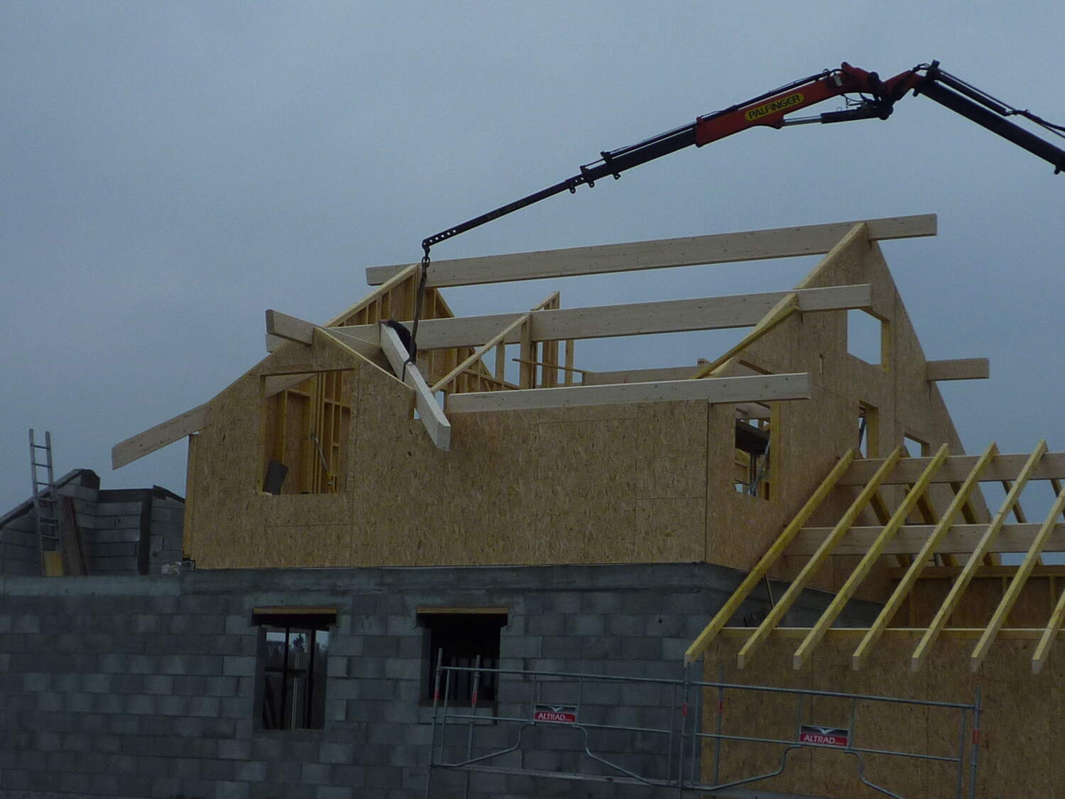 Charpentier installant des fermes de toit sur un chantier de construction.