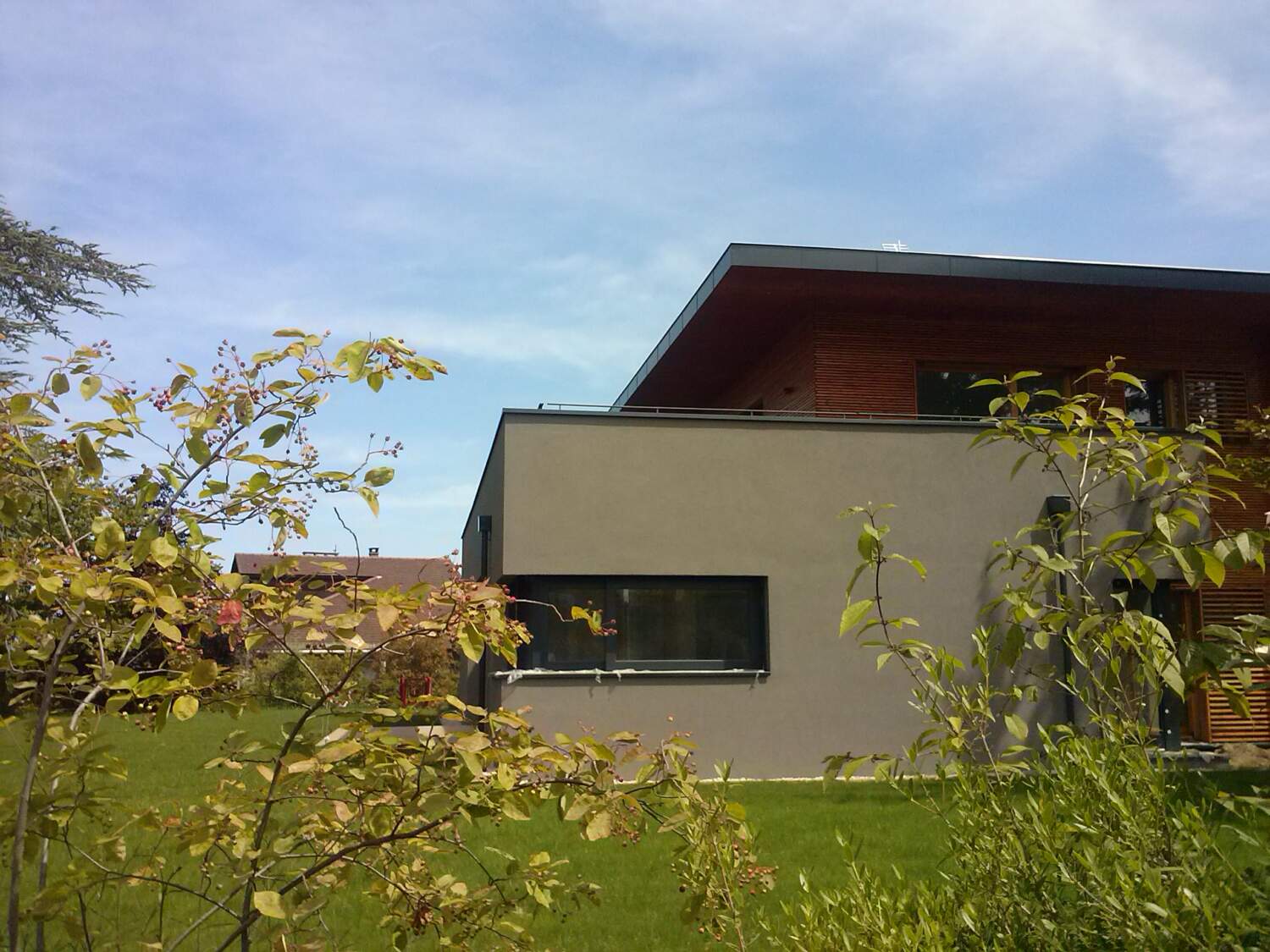 Extérieur de maison moderne avec bardage en bois et grandes fenêtres.