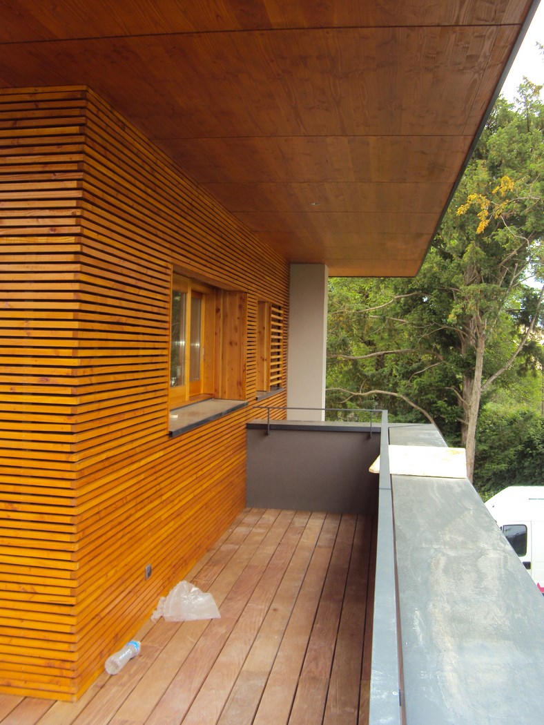 Charpentier installant un bardage en bois sur l'extérieur d'une maison.