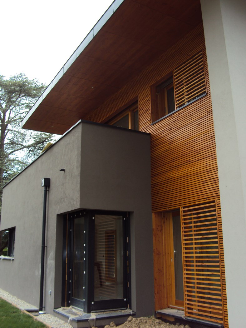 Maison moderne avec bardage en bois et grandes fenêtres.