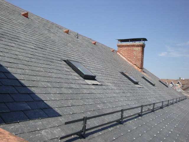 Installation d'une toiture en ardoise sur un chantier de construction.