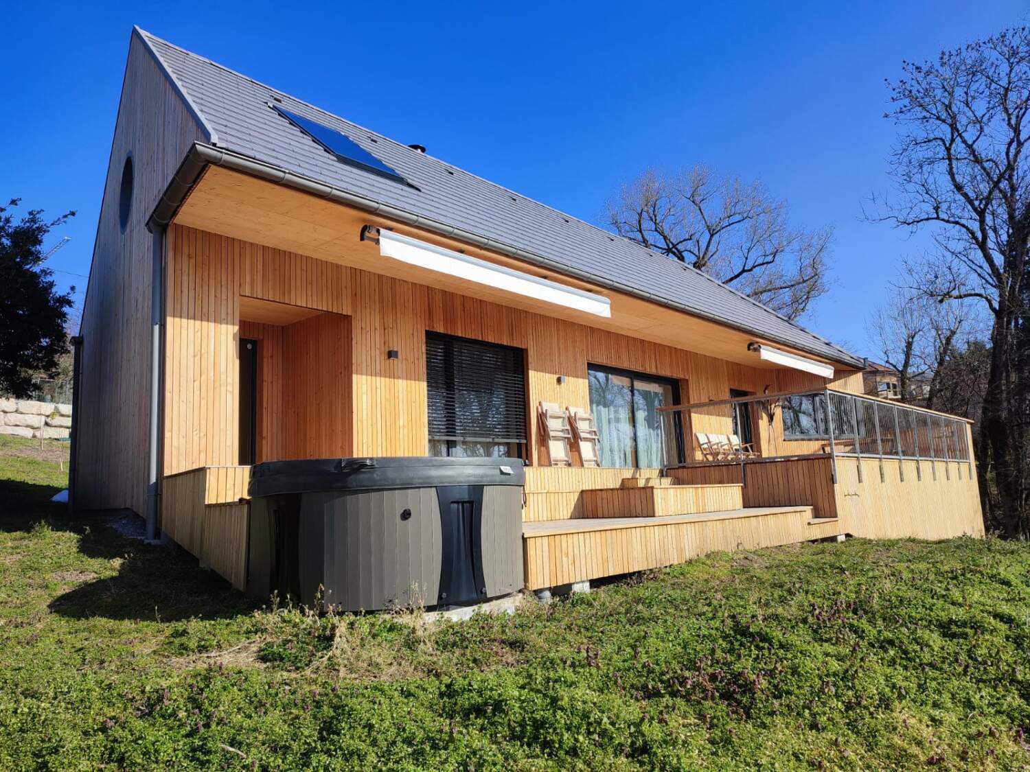 Extérieur de maison en bois avec bardage et installation de terrasse.