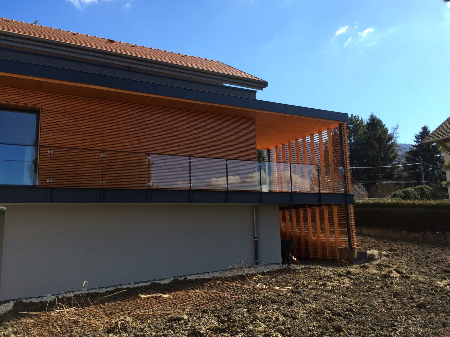 Charpentier installant un bardage en bois sur l'extérieur d'une maison.