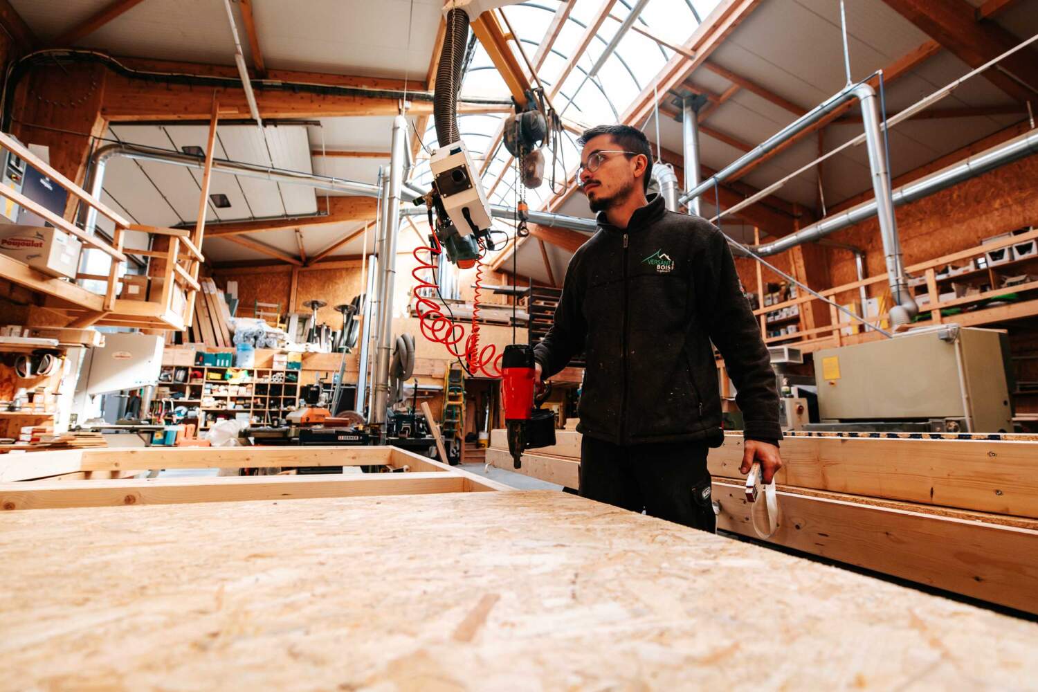 Charpentier entrain de travailler sur une ossature bois dans un atelier de charpente